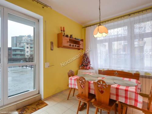 d'une salle à manger avec une table, des chaises et une fenêtre. dans l'établissement Apartament W sercu Krynicy, à Krynica-Zdrój