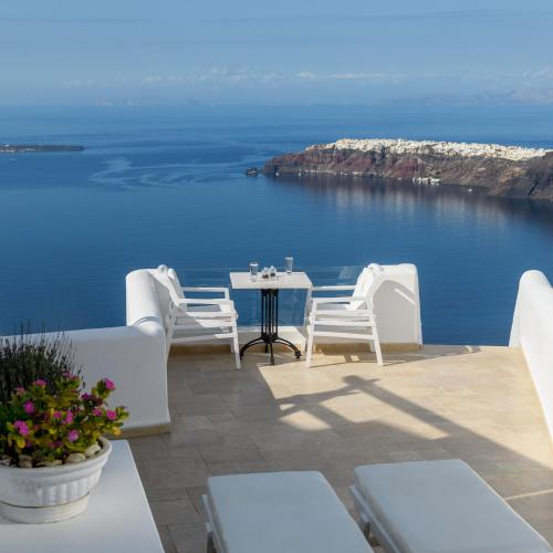a patio with a table and chairs overlooking the ocean at Above Blue Suites in Imerovigli