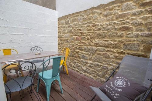 - une table et des chaises dans une pièce dotée d'un mur en briques dans l'établissement La Vedette - Les Gîtes de KEROUZEC - Mer et centre historique, à Port-Louis