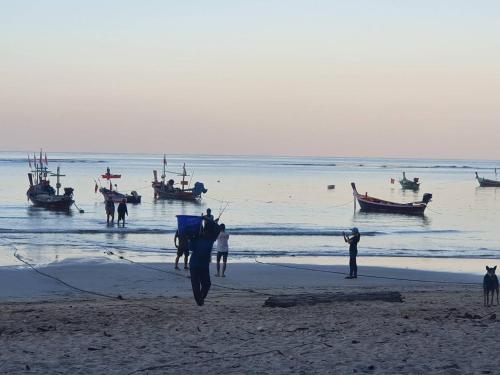 a group of people on a beach with boats in the water at Atom Phuket Hotel in Nai Yang Beach
