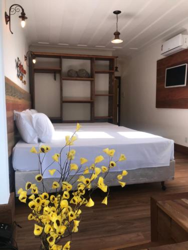 a bedroom with a bed with yellow flowers in the foreground at Hotel Recanto do Ouro in Ouro Preto