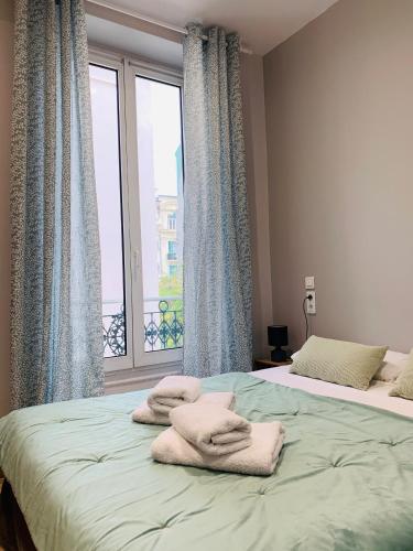 a bedroom with two beds and a large window at Hotel le Nice Etoile in Nice