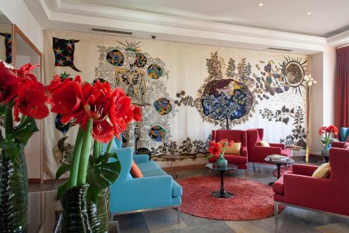 a lobby with red and blue chairs and red flowers at La Residence Du Vieux Port in Marseille