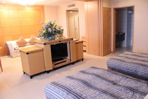 a hotel room with two beds and a tv at Grand Hotel Hakusan in Hakusan