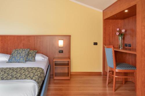 a hotel room with a bed and a chair at Hotel Postumia in Dossobuono