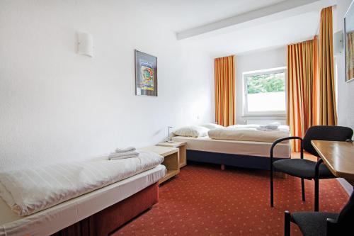 a room with two beds and a table and a desk at Baltic Hotel Lübeck in Lübeck