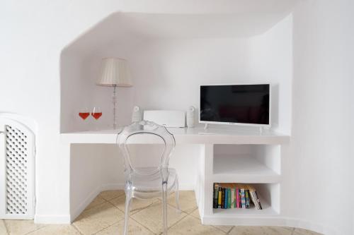 a white desk with a tv and a chair at Above Blue Suites in Imerovigli