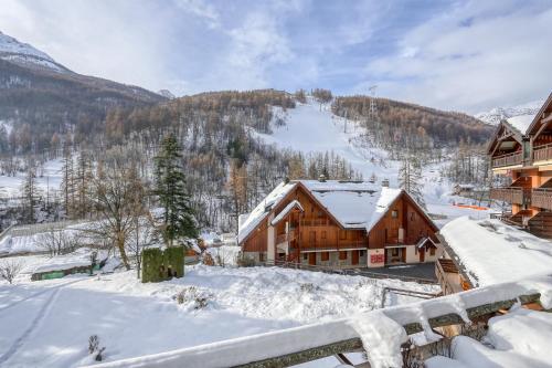 a log cabin in the snow with a ski slope at Prestigieux Appartement Pied Piste Luc Alphand 80 M2 Serre Chevalier Chantemerle in Saint-Chaffrey