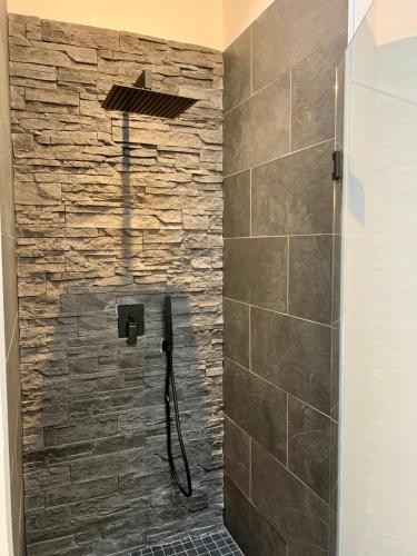 La salle de bains est pourvue d'une douche et d'un mur en pierre. dans l'établissement Victoria's House, à Lille