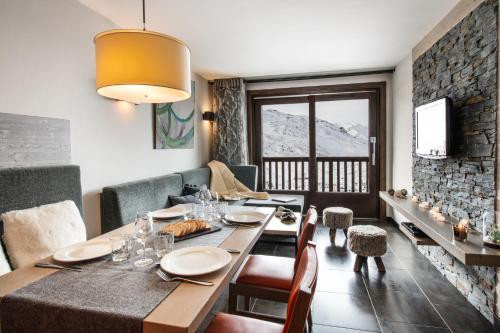 a dining room with a table and chairs and a stone wall at Residence Montana Plein Sud in Val Thorens