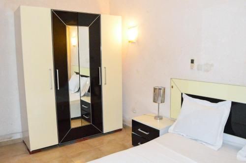 a bedroom with a large mirror cabinet next to a bed at Résidence Hotelière Borel Denver in Douala