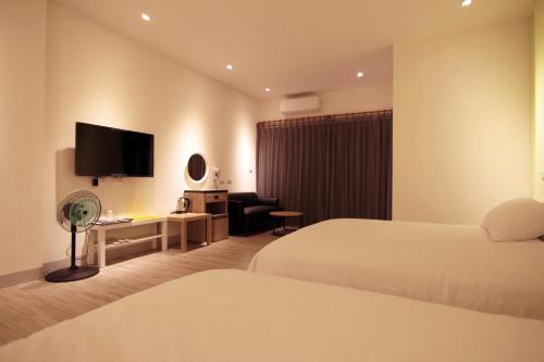 a hotel room with two beds and a flat screen tv at Haichin&Haiting B&B in Donggang
