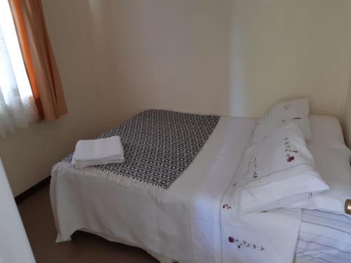 a bed with white sheets and pillows in a room at Departamentos Berna in Valdivia