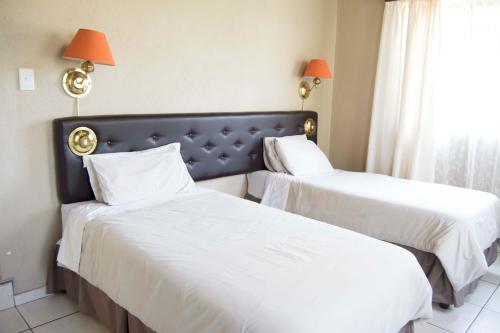 two beds in a hotel room with white sheets at Floreat Riverside Lodge and Spa in Sabie
