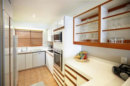 a kitchen with white cabinets and a sink at Pioneer Waterfront Apartments in Paihia