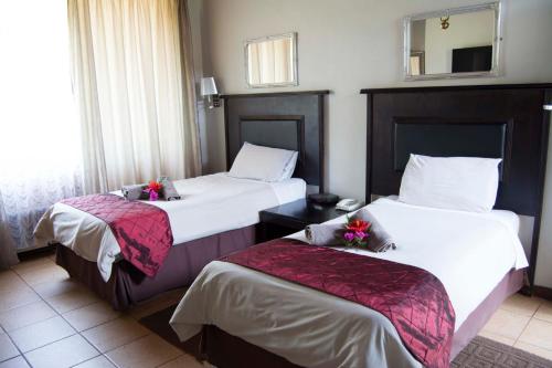 a hotel room with two beds and a mirror at Floreat Riverside Lodge and Spa in Sabie