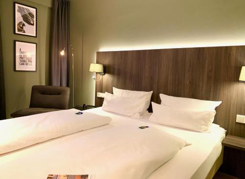a hotel room with a large bed with white pillows at zeitwohnhaus SUITE-HOTEL & SERVICED APARTMENTS in Erlangen