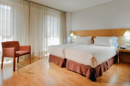 a hotel room with a large bed and a chair at Hesperia Zaragoza Centro in Zaragoza