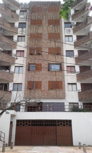 un grand bâtiment avec une porte brune devant lui dans l'établissement Departamento Centro Villa Carlos Paz, à Villa Carlos Paz