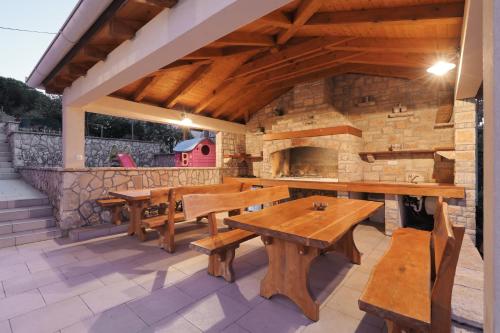 Villa Bobic في Kraj: فناء في الهواء الطلق مع طاولات خشبية وجدار حجري