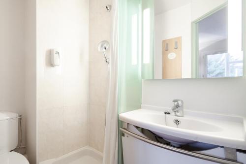 een badkamer met een wastafel, een toilet en een spiegel bij B&B HOTEL Montlhery in Linas