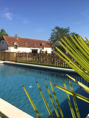 uma piscina em frente a uma casa com uma cerca de madeira em Village Toue du Domaine des Demoiselles em Chassenard