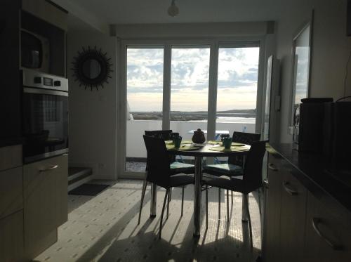 une table et des chaises dans une cuisine avec une fenêtre dans l'établissement Au Bord Du Chenal, à Porspoder
