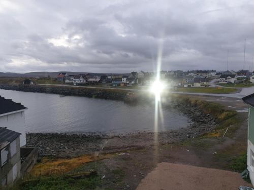 a sun shining on a body of water with houses at Kristian 4. Gt. apartement in Vardø