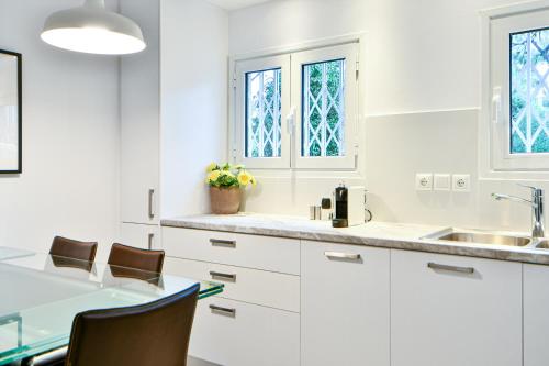 - une cuisine avec des placards blancs, une table et des chaises dans l'établissement Boutique77 Luxury Apartment, à Athènes