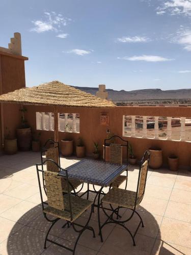 a table with chairs and an umbrella on a patio at Berber Nomad Kasbah in Nkob