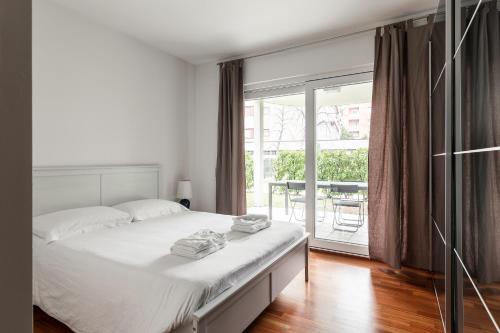 una camera bianca con letto e balcone di Prestige Apartments by Quokka 360 - spacious flats with terraces a Lugano