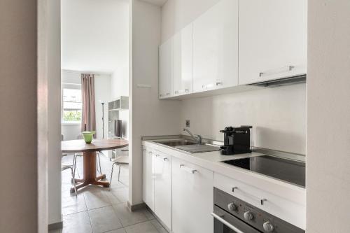 a kitchen with white cabinets and a sink and a table at Prestige Apartments by Quokka 360 - spacious flats with terraces in Lugano
