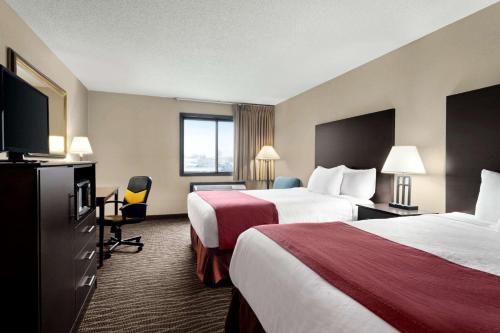 a hotel room with two beds and a flat screen tv at Baymont by Wyndham Sioux Falls North,I-29,Russell St, Airport in Sioux Falls