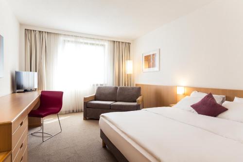 a hotel room with a bed and a chair at Novotel Düsseldorf City West in Düsseldorf