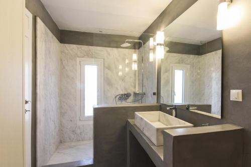 baño con lavabo y espejo grande en 67sq meters modern apartment with a swimming pool and sea view in Koundouros en Koundouros