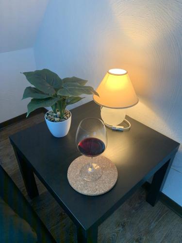a table with a glass of wine and a lamp at DIE Mansarde ! in Saarbrücken