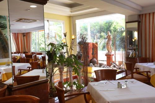 restauracja z białymi stołami i krzesłami oraz pomnikiem w obiekcie Hotel Manaus w El Arenal