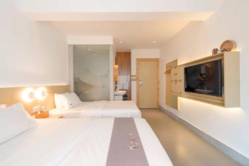 a hotel room with two beds and a flat screen tv at Zen Tea House Elephant Trunk Hill Park船舍茶椐象山店 in Guilin