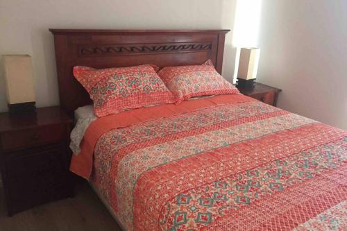 - un lit avec une couette rouge et 2 oreillers dans l'établissement Departamento En Papudo, à Papudo