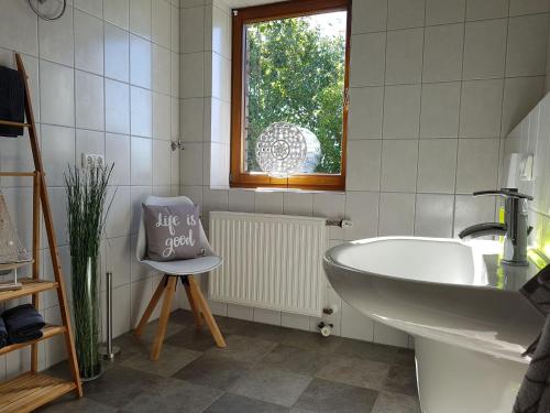 y baño con bañera, lavamanos y silla. en Garden & Hill Ferienwohnung Limburg, en Simmerath