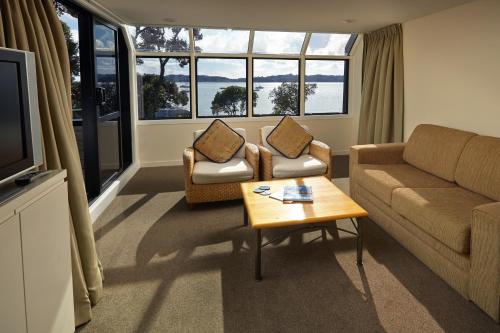 a living room with a couch and a table at Pioneer Waterfront Apartments in Paihia