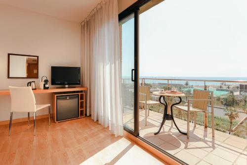 a room with a balcony with a desk and a television at Hesperia Barcelona Del Mar in Barcelona