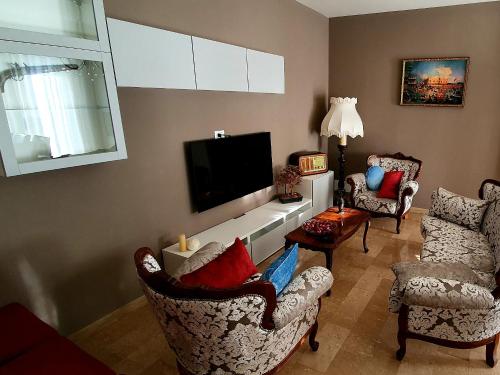 a living room with two chairs and a flat screen tv at Arianna Apartments in Vittorio Veneto