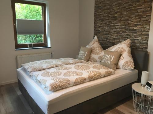 uma cama com almofadas num quarto em Garden & Hill Ferienwohnung Limburg em Simmerath
