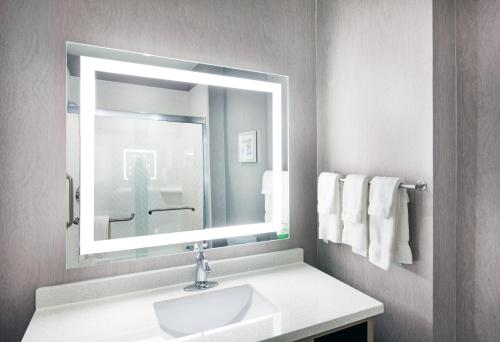 uma casa de banho com lavatório, espelho e toalhas em Holiday Inn Lubbock South, an IHG Hotel em Lubbock