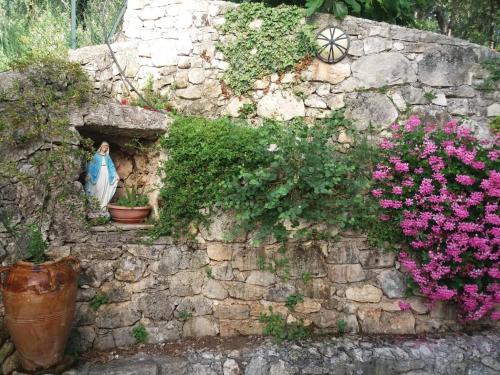 a statue of a woman in a niche in a stone wall with flowers at La casa di Antonella in Vico del Gargano