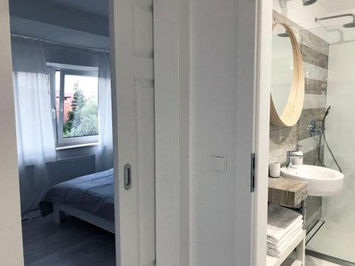 a white bathroom with a sink and a mirror at Morska Kryjówka in Niechorze
