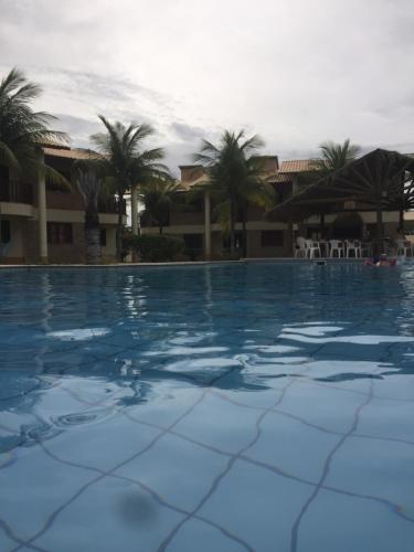 uma grande piscina com palmeiras ao fundo em Club house em Prainha