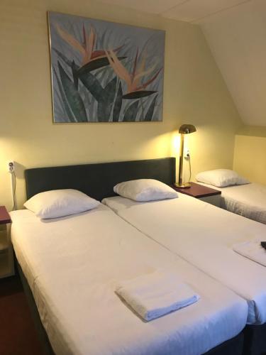 2 Betten in einem Hotelzimmer mit Handtüchern darauf in der Unterkunft Hotel De Weyman in Santpoort-Noord