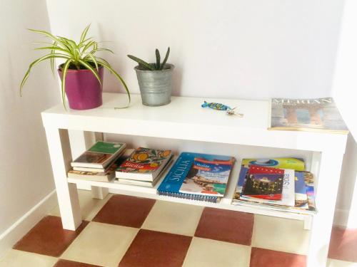 a white table with books and a potted plant at Il giardino delle zagare - miniappartamento tra Etna e mare in Riposto